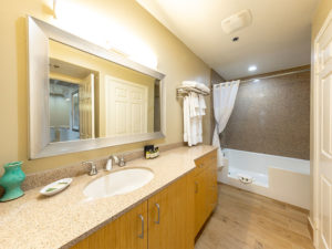 bathroon sink with mirror, white towels and shower/tub