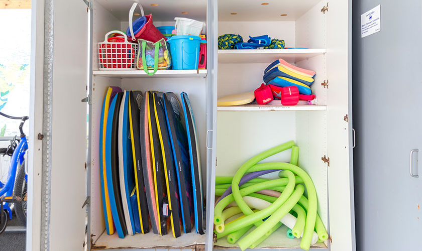 storage cabinet with beach supplies - boogie boards, sand buckets, and pool noodles