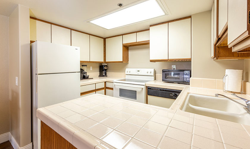 full kitchen white tile countertops, white appliances and white and light wood cabinets
