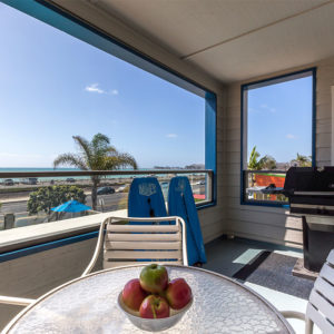 balcony ocean view, bbq grill, glass patio table with white patio chairs and two blue boogie boards