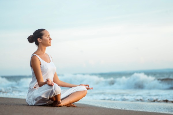 woman sitting on the beach doing yoga