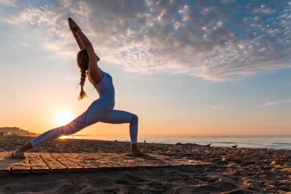 woman on the beach doing yoga at sunset